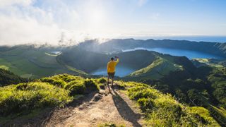 Man on top of a mountain photographing volcanoes in Sao Miguel, Azores