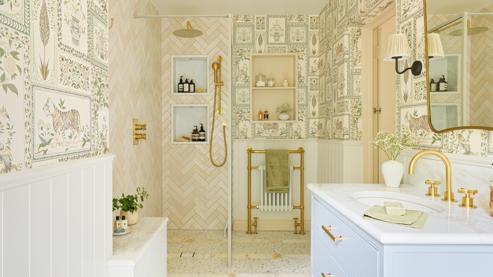A large shower room with tiger-themed wallpaper, a glass shoer screen, pink shower tiles, and brass fixtures