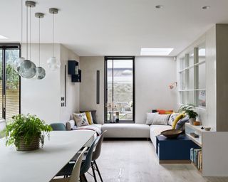 Open plan dining, living area in neutral colours with a pale wooden floor and windows looking out onto the garden.