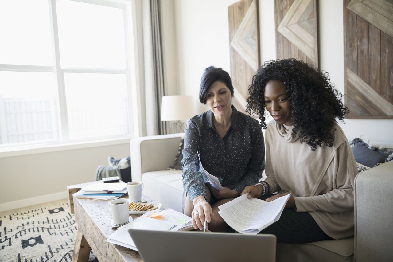 Financial advisor with laptop and paperwork meeting with woman in living room