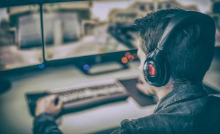 Young man wearing headphones plays video game on computer