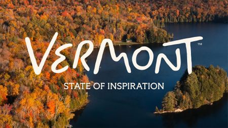 Aerial view of a forested Vermont lake in autumn colours, overlaid with the hand-lettered "Vermont" wordmark and the strapline "State of Inspiration".
