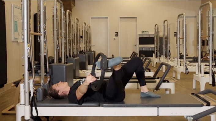 Woman on a Reformer Pilates machine demonstrating an exercise