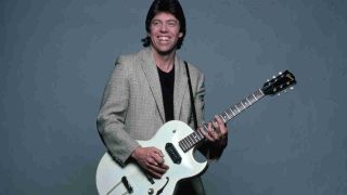 George Thorogood posing for a photograph with a guitar in the early 1980s