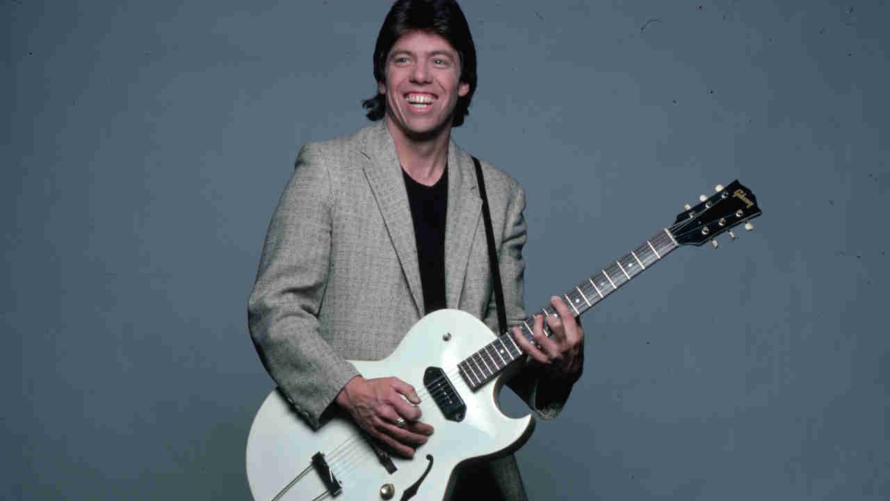 George Thorogood posing for a photograph with a guitar in the early 1980s