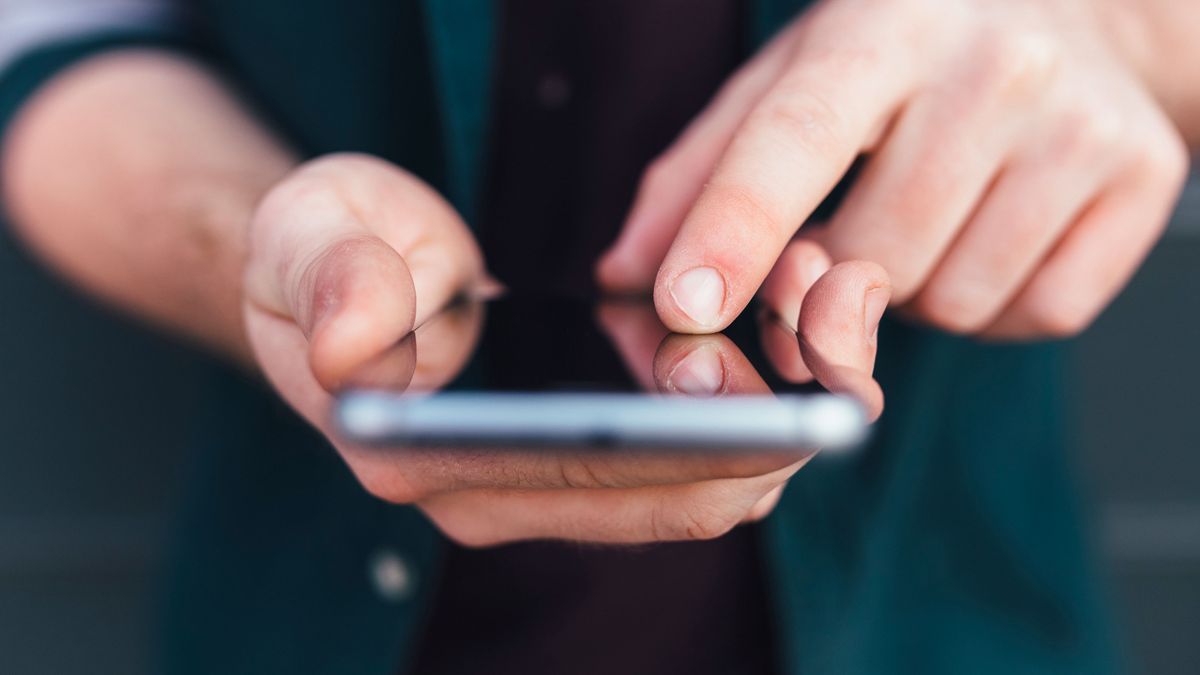 Index finger of young man touching smartphone 