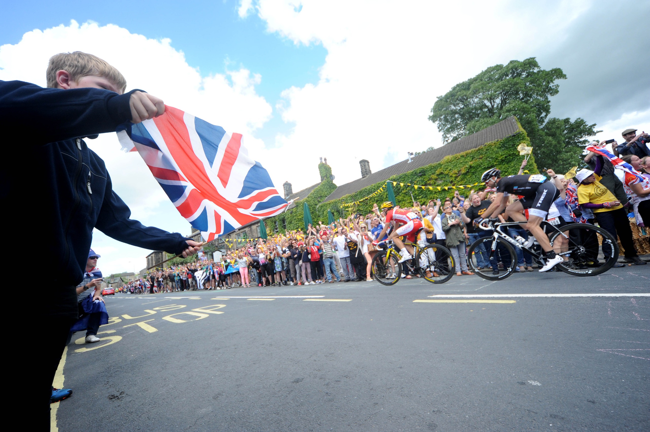 A boy waving a Union Jack at the passing Tour de France peloton in Harrogate in 2014