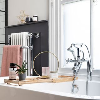 Monochrome bathroom with freestanding bath, traditional chrome taps, bamboo bath caddy, wall panelling and Victorian radiator