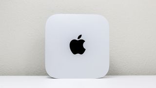 The Mac mini M4 upright on a desk showing the Apple logo