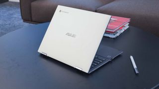 En Asus Chromebook Flip CM3 står placerad på ett mörkt bord. Sedd snett bakifrån.
