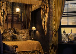 Gold-themed room with four-poster bed, fancy pillows and open window with views of Edinburgh in The Witchery