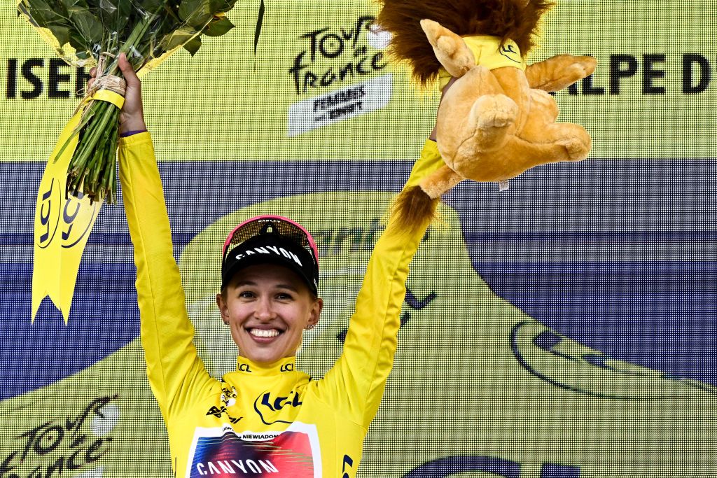 Canyon//SRAM Racing team's Polish rider Katarzyna Niewiadoma celebrates on the podium wearing the overall leader's yellow jersey after winning the third edition of the Women's Tour de France cycling race and competing in the 8th and last stage of the Women's Tour de France cycling race, a 149.9 km between Le Grand Bornand and the Alpe d'Huez, in L'Alpe d'Huez, south-eastern France, on August 18, 2024. (Photo by JULIEN DE ROSA / AFP)