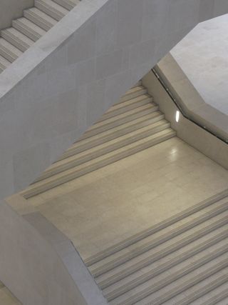 A view of the concrete beige staircase with black banister photographed from above