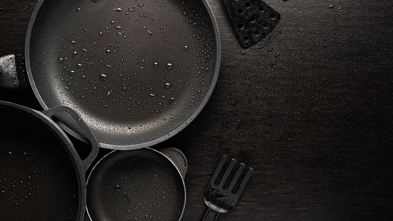 Non stick pans on a black work top sprayed with oil