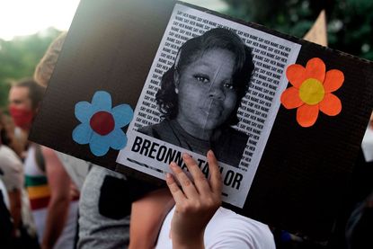 A protester holds a sign with Breonna Taylor's picture.