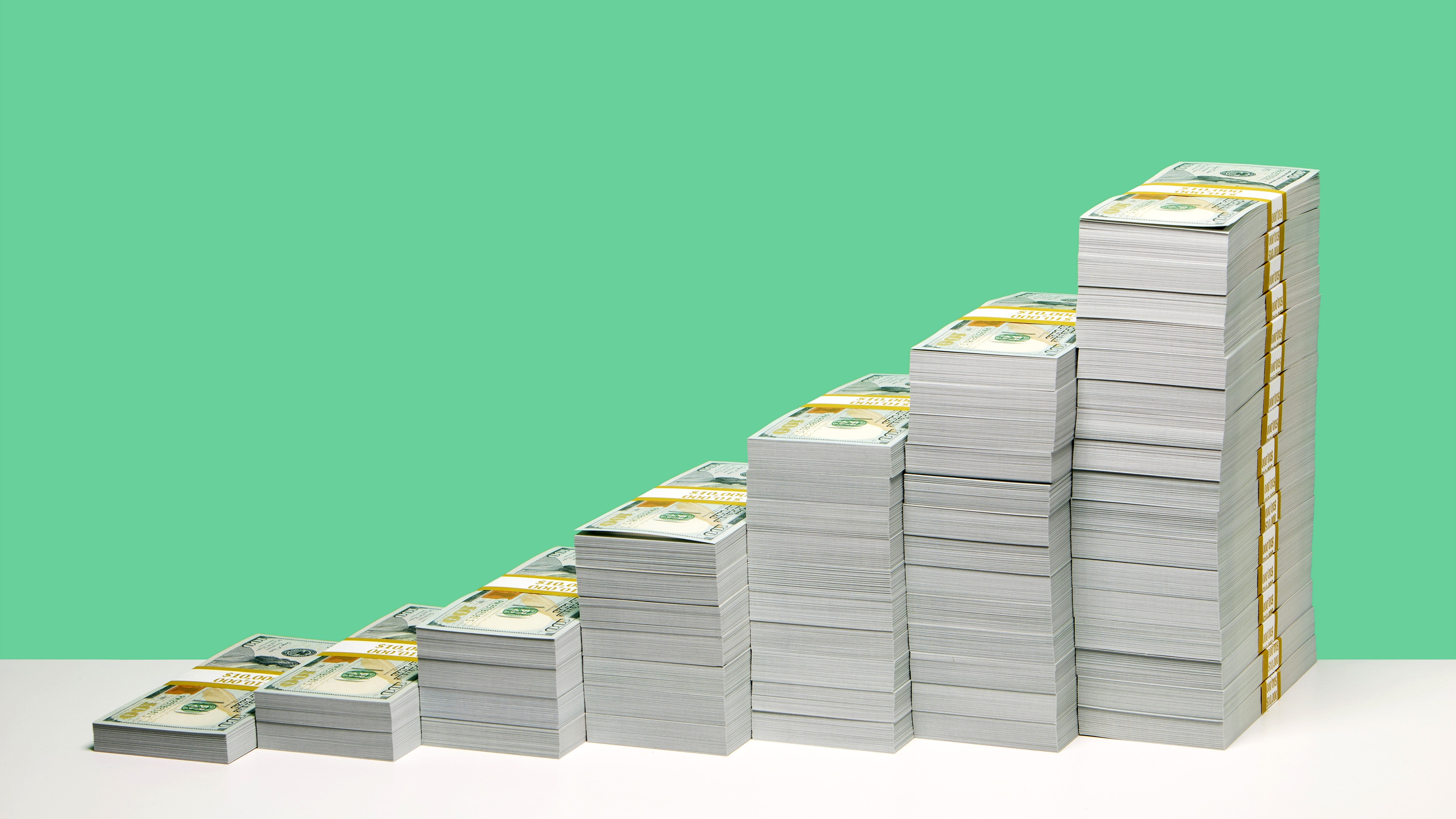 Subsequently taller stacks of cash against a bright green background.