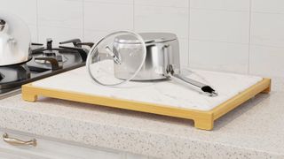 A stone drying mat on a kitchen worktop with a pan and pan lid drying on it
