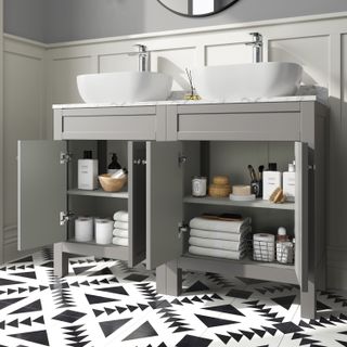 double sink unit in grey with open doors showing storage, black and white tiled floor