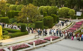 A queue of people through the middle of a landscaped garden