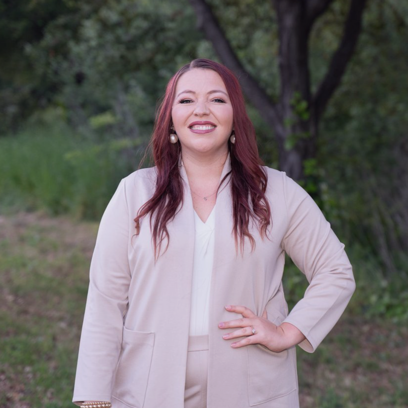 a photo of Dr Courtney Crisp standing outside in a light pink suit