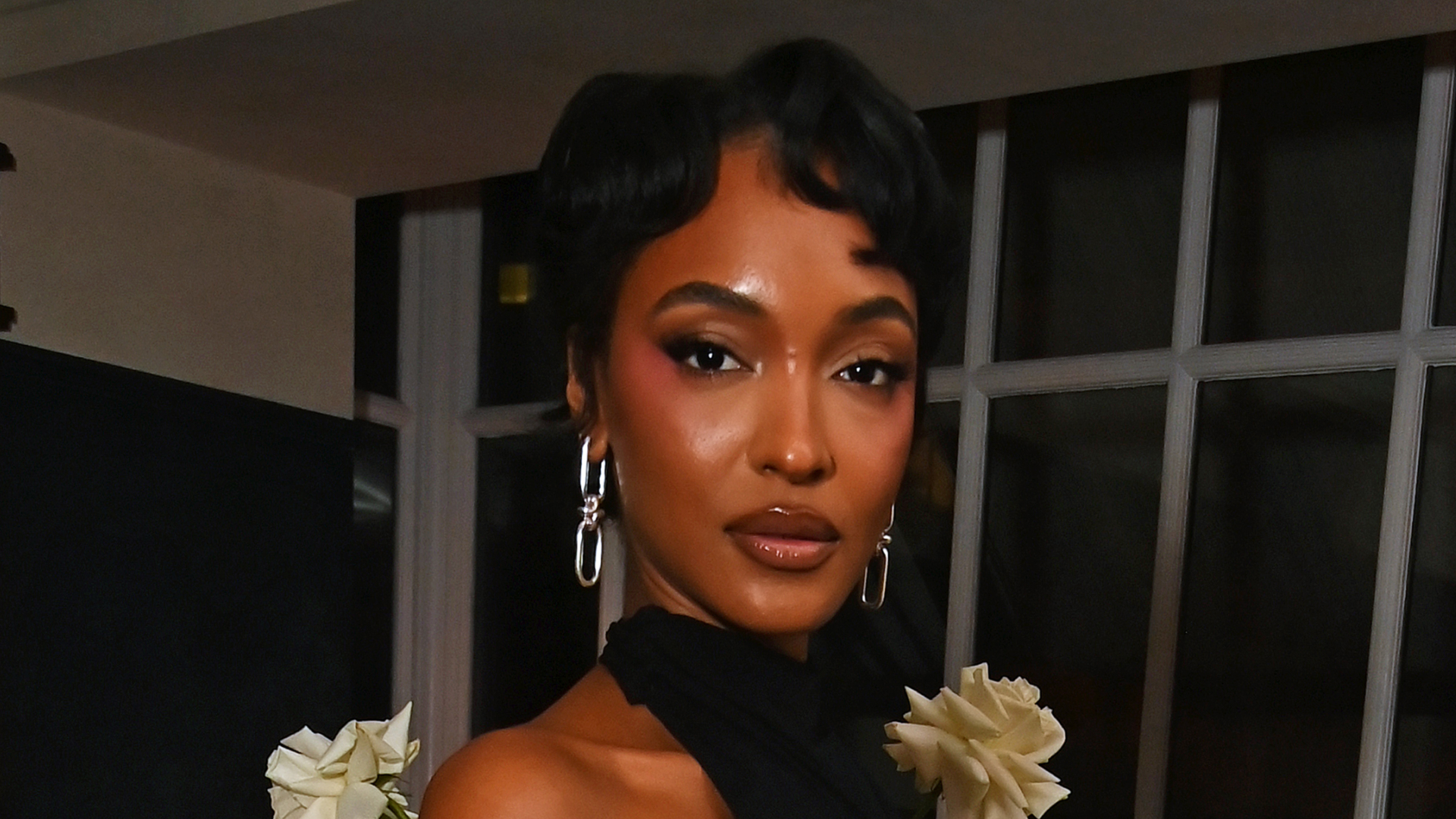A woman with short hair that has finger waves in it, wearing a turtle neck halter top.