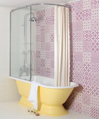 yellow rolltop bath with pink wall tiles
