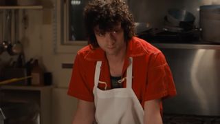 Dominic Sessa in a red shirt and white apron in Tony