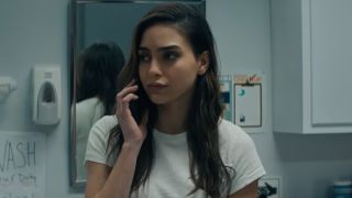 Melissa Barrera holding up a phone and looking to her left in Scream. 