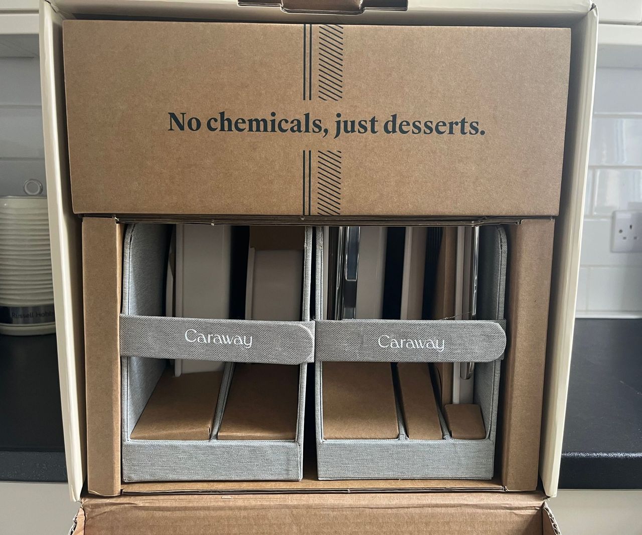 A box of Caraway bakeware on a black kitchen counter.