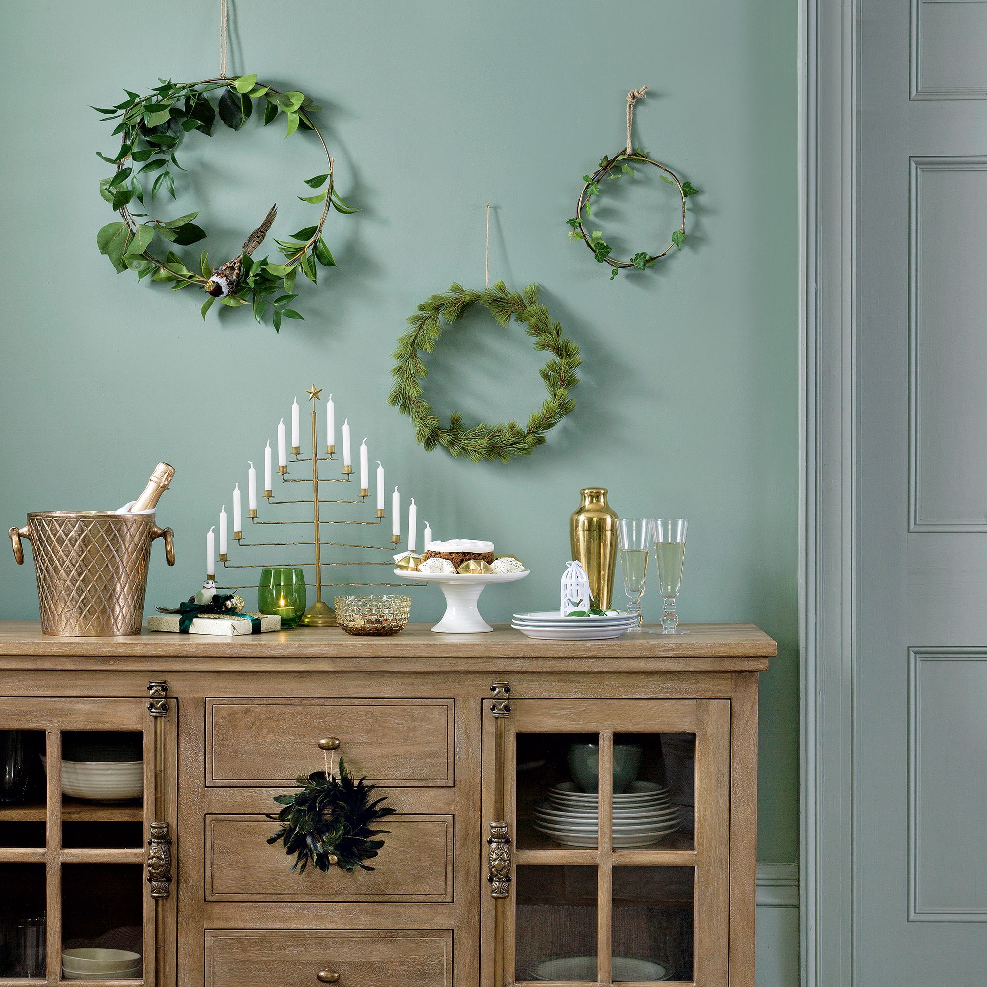 Green dining room with a wooden sideboard against the wall, used for a display of party drinks and cakes