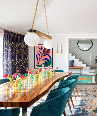 dining room with teal chairs, wooden long table and pink artwork on wall