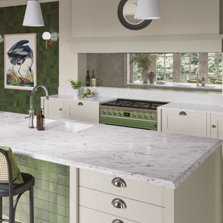 Green kitchen with marble counters and mirrored backsplash.