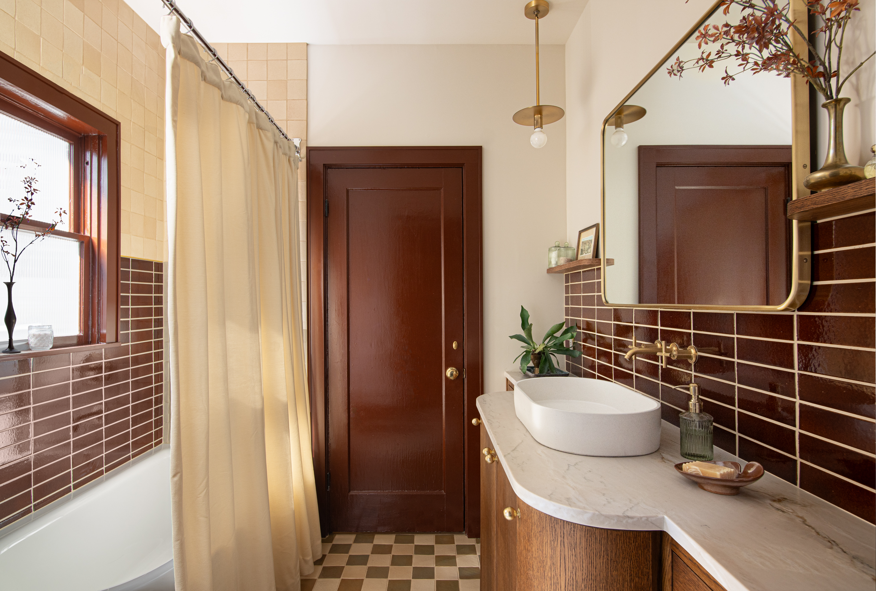 Bathroom with dark red tiles, checkerboard floor, gold mirror and light, marble countertop