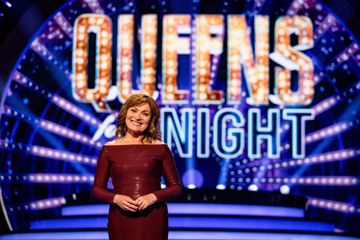 Lorraine Kelly stands in the Queens For The Night studio in front of a screen displaying the show&#039;s logo