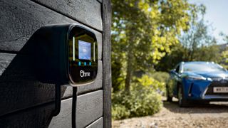 Ohme Home Pro charger on a house with an EV in the background