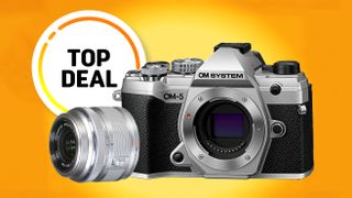 Silver OM System OM-5 camera with a separate lens against a vibrant orange background. A "Top Deal" badge in black and white is nearby, conveying excitement