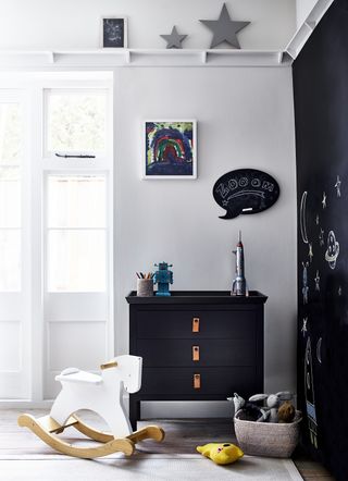boys bedroom with black and white scheme, black chest of drawers, black chalk board with drawings on