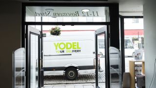 Delivery van with Yodel logo photographed through a shop door frame