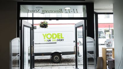 Delivery van with Yodel logo photographed through a shop door frame