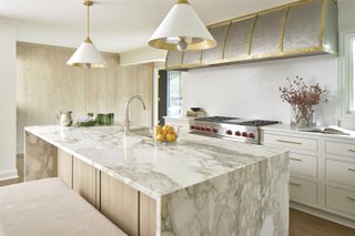 A marble kitchen island with a sink and two pendant lights hanging above it