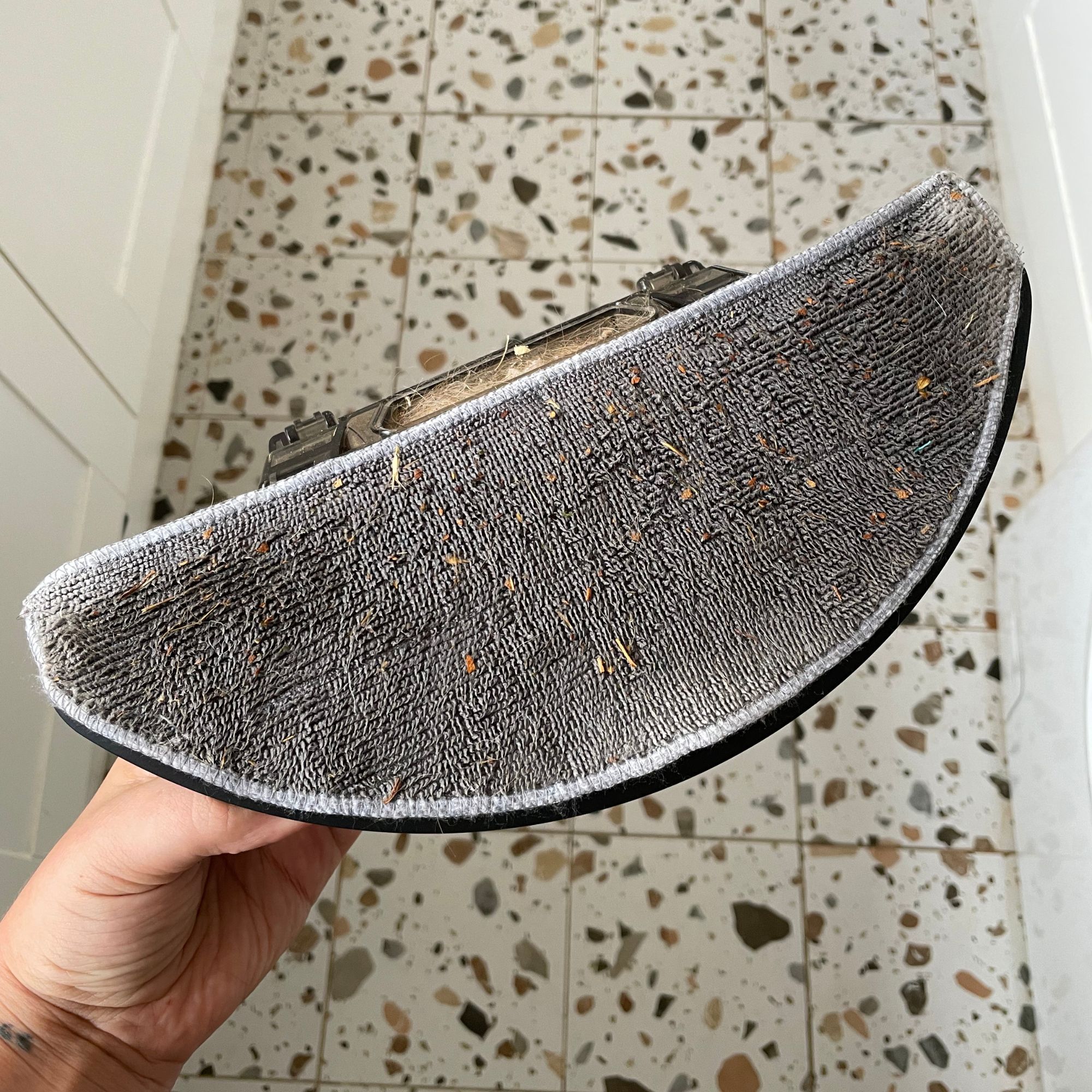 Hand holding a wet and dirt mop pad of the Hoover HG2 robot vacuum and mop