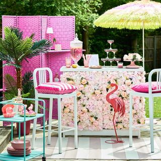 outdoor bar with faux floral panels, bar stools and parasol for Barbiecore trend