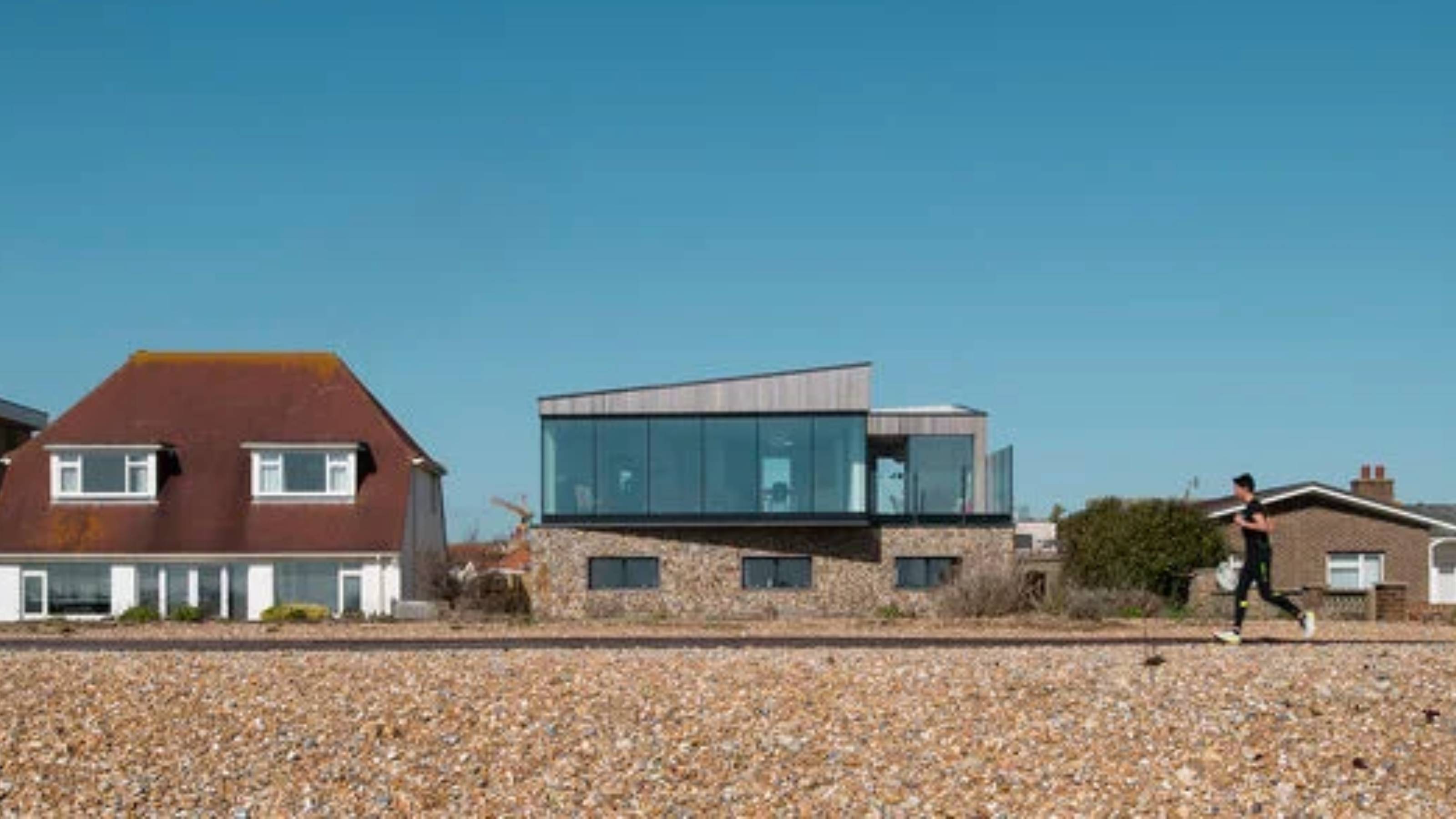 solar control glass on modern coastal house with woman running on beach