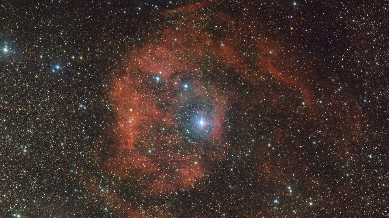 A reddish haze against a very starry gray sky.