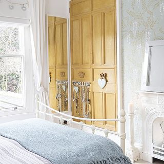 bedroom with blue designed wall wooden cupboard and white bed