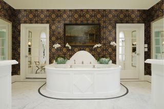 Bathroom with white central tub and wallpaper in brown and black by Timothy Corrigan
