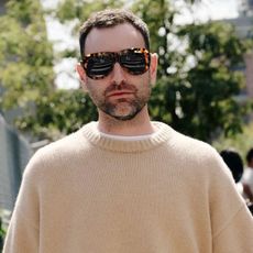 Bobby wears sunglasses and a crewneck sweater.