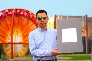 Xiulin Ruan, a professor of mechanical engineering at Purdue University holds up a sample of the whitest paint.