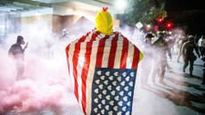 Protester in chicken costume stands amid tear gas outside ICE facility in Portland, Oregon