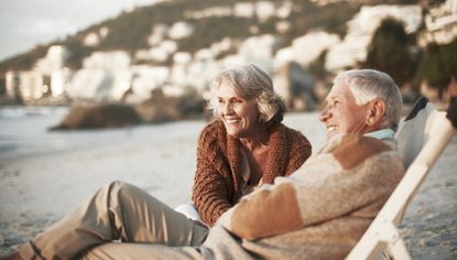 Happy senior couple relaxing on deck chairs at beach